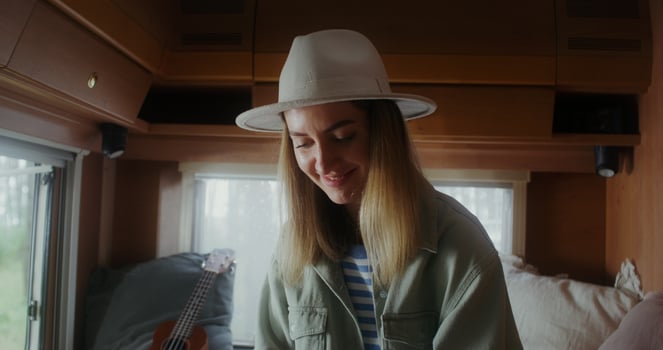 A young woman in a hat smiles sitting on a bed in a van photo