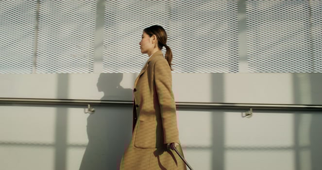 A woman in a coat with luggage in her hand walks through the railway station with a concentrated look - railway photo