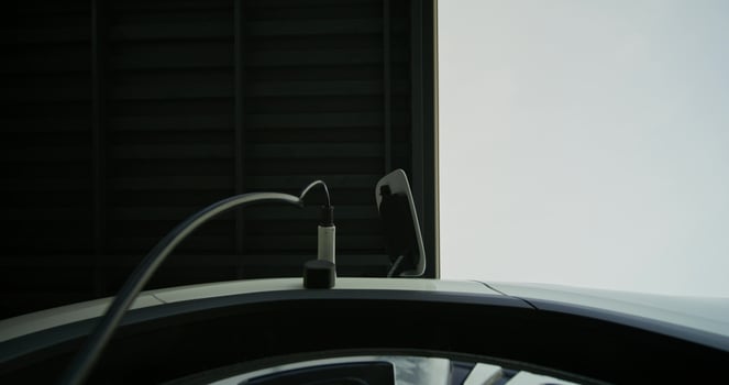 A man in casual clothes disconnects charging from an electric car, bottom view photo