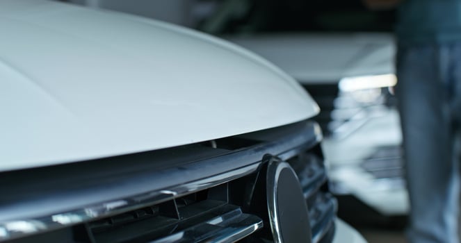 The car dealership manager is talking to the customer standing next to the car. He opened the hood of the car, Close-up of his hands, unrecognizable persons photo