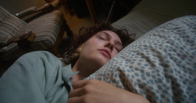 A woman is crying and hugging a pillow lying in bed at home. The mascara is smeared under the eyes - pillow photo