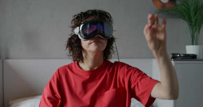 A woman wearing a red shirt and holding up a virtual reality headset photo