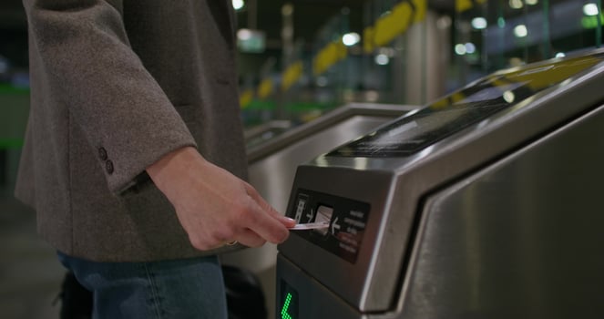 A woman inserts a card into a subway terminal and passes through. close-up of her hand, an unrecognizable person photo