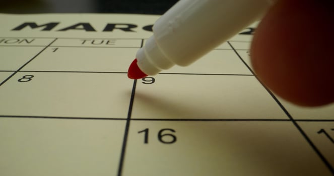 A person is writing on a calendar with a red marker photo