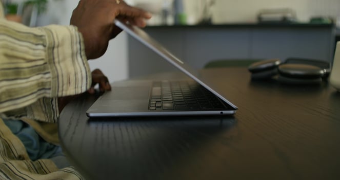 A man opens a laptop and starts typing while sitting at a table at home. Close-up of his hands, an unrecognizable person photo