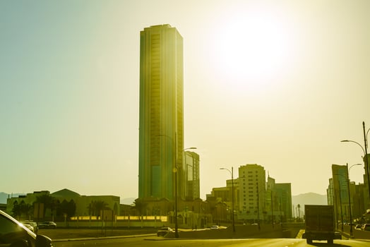 A car driving down a street with a tall building in the background photo