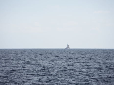 The boundless expanse of the sea with gentle waves shimmering in the sunlight. In the distance, on the horizon photo