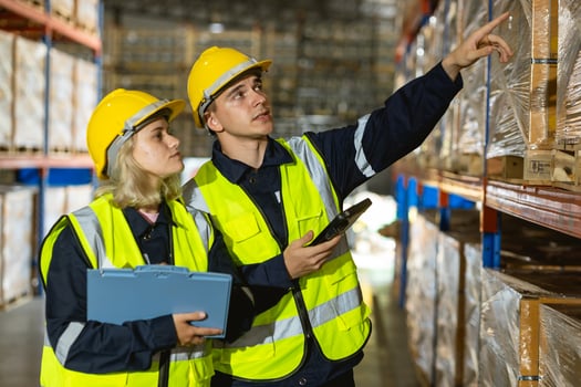 Two workers in safety vests looking at a clipboard photo
