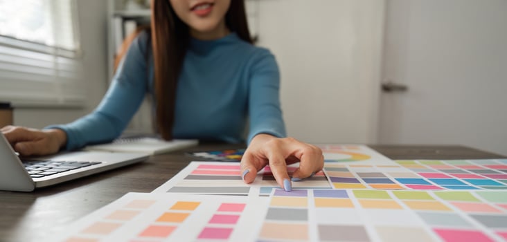 Color Exploration and Digital Design. A professional evaluating vibrant color choices using swatches and a laptop. photo