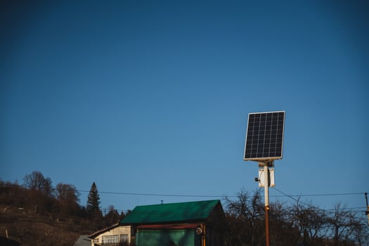 There is a quaint little house that features a charming green roof, along with a solar panel strategically placed in front of it, harnessing energy from the sun for sustainable power photo