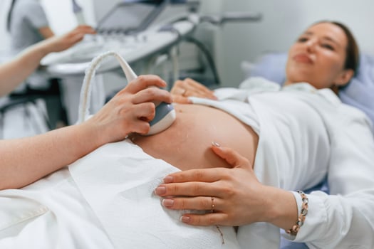 Pregnant woman is, lying ,down in the hospital, doctor does ultrasound photo
