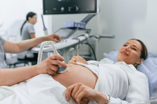 Smiling, medical ,procedure,. Pregnant woman, is lying down in the hospital, doctor does ultrasound photo
