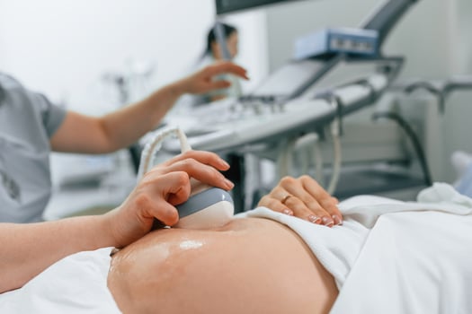 Focused close up view. Pregnant ,woman i,s lying down in the hospital, doctor does ultrasound photo