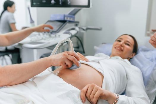 Smiling, medical procedure. Pregnant, woman ,is lying down in the hospital, doctor does ultrasound photo
