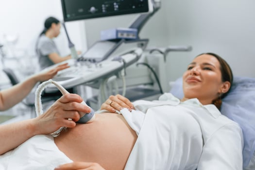 Close, up view, scanning. Pregnant woman is lying down in the hospital, doctor does ultrasound photo