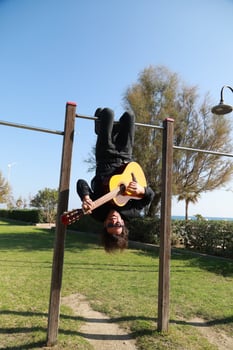 Young Man Plays Guitar Music Hanging Upside Down In An Outdoor Park Outdoor photo