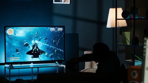 Guy playing online tournament and winning round, plugging console into television and having fun with successful competition at night. First person shooter. Camera B. photo