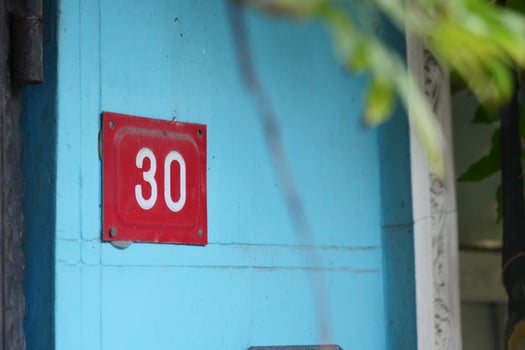 Bright blue wall with red house number thirty in urban area photo