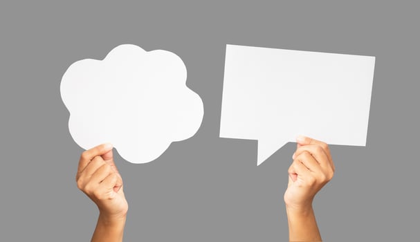 Close-up of hands holding a white speech bubbles against a gray background photo
