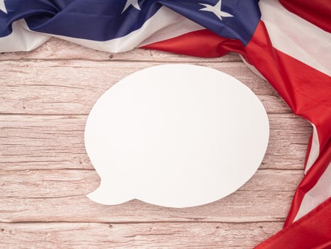Top view of the American flag with blank white a speech bubble over a wooden table. Space for text. photo