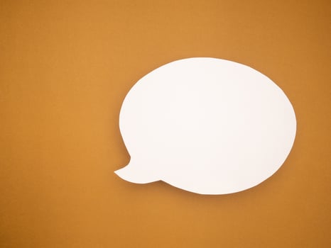 A blank white speech bubble on a brown background photo