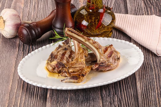 Grilled lamb chops on a white plate with garlic and herbs photo