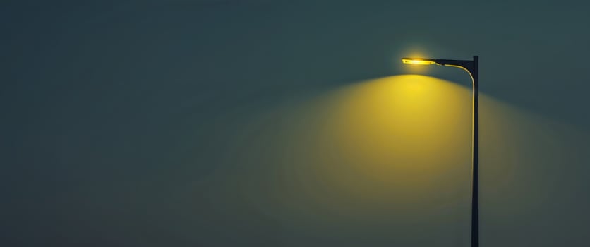 A street lamp with a yellow light is lit up in the night photo