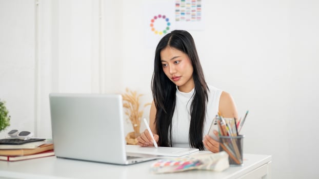 An asian woman is holding a stylus pencil drawing or writing on the tablet. Designer at work. photo