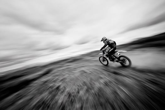 A black and white photo of a person riding a dirt bike