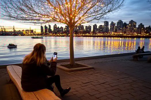 A woman sitting on a bench looking at her cell phone photo