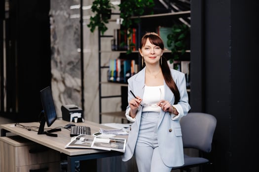 Businesswoman in blue suit leans on desk in modern office. photo