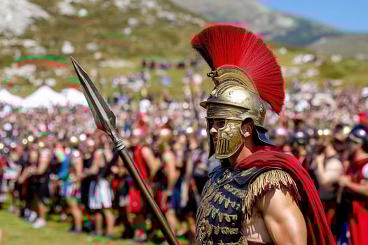 A man in a spartan costume is standing in front of a crowd photo