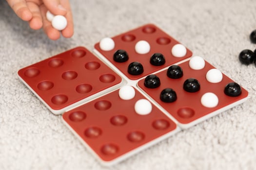 Kids take turns placing black and white marbles on the board, each move carefully planned. The game brings joy and challenges as they strategize to win. photo