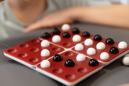 Kids place black and white marbles on the board, carefully planning each move. The game offers them a chance to learn strategy while having fun together. photo