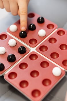 Family Game Time. A fun tabletop game brings together children and their friends, as they place marbles on the board. It's a moment of joy, strategy, and friendship. photo