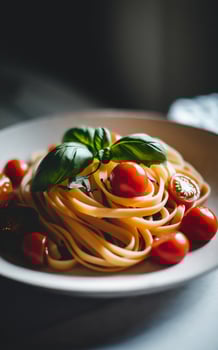 A plate of linguine pasta is beautifully garnished with fresh cherry tomatoes and basil leaves. photo
