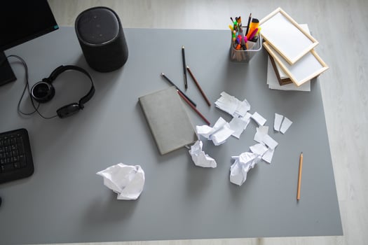 Messy home office desk with scattered paper and supplies. Creative block, frustration and domestic disorder in a modern living space. photo