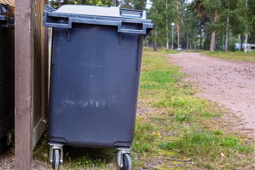 A black garbage trash bin in a forest area. Waste management in mature Waste sorting management in an camping environment. Sustainable waste disposal system. Outdoor trash storage. Finland, Hamina photo