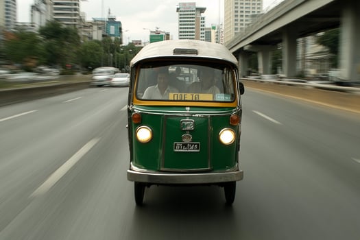A small green and white vehicle driving down a road photo