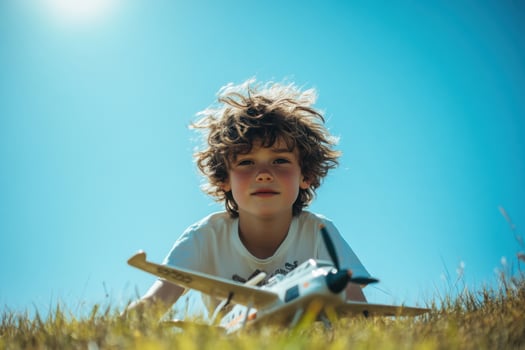 Young boy playing with toy airplane in meadow during sunny day photo