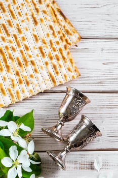 Happy Passover flatlay. Jewish matzo bread and wine glasses on white background photo