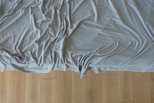Messy bed with wrinkled gray sheets in a cozy room photo