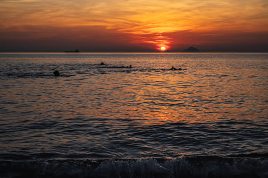 Silhouettes of people swimming in sea at sunrise in the morning on vacation at a resort in summer photo
