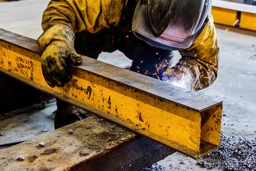 A welder in action, welding a steel structure in a factory setting, with bright sparks and smoke filling the air, capturing the intensity and skill involved in the process photo