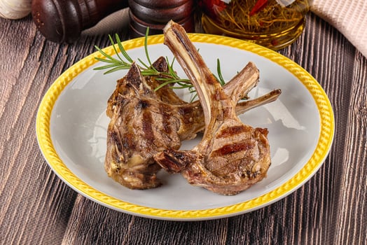 Grilled lamb chops on a white plate with herbs and spices photo