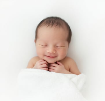A newborn boy wrapped in a white blanket photo