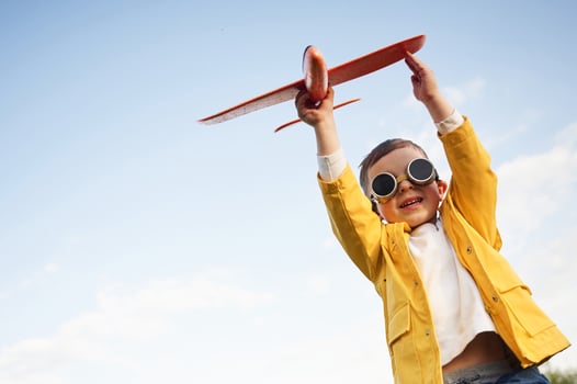 Aviator glasses are worn. Little boy ,is ,playing with toy plane on the summer field photo