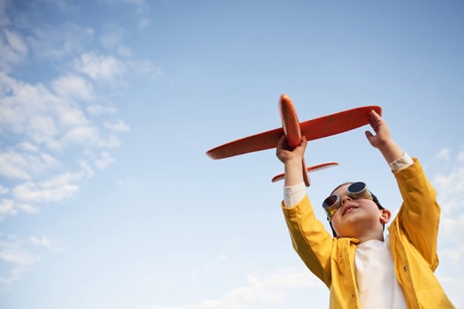 Aviator glasses are worn. ..Little boy is playing with toy plane on the summer field photo