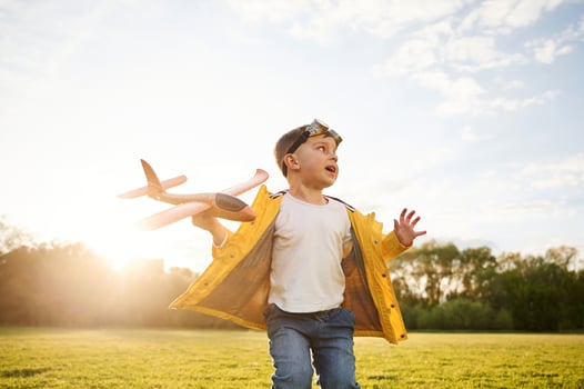 Against sky, with amazing sunshine.. Little boy is playing with toy plane on the summer field photo