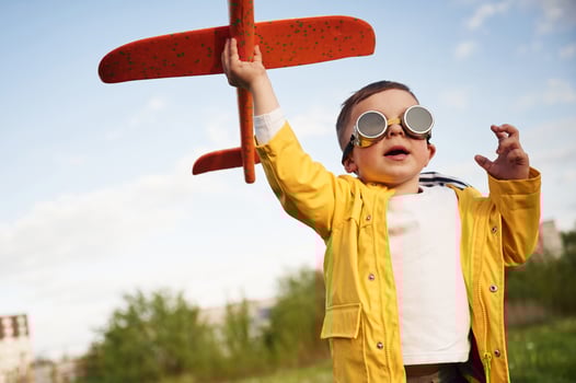 Red, colored toy plane.. Little boy is playing on the summer field photo